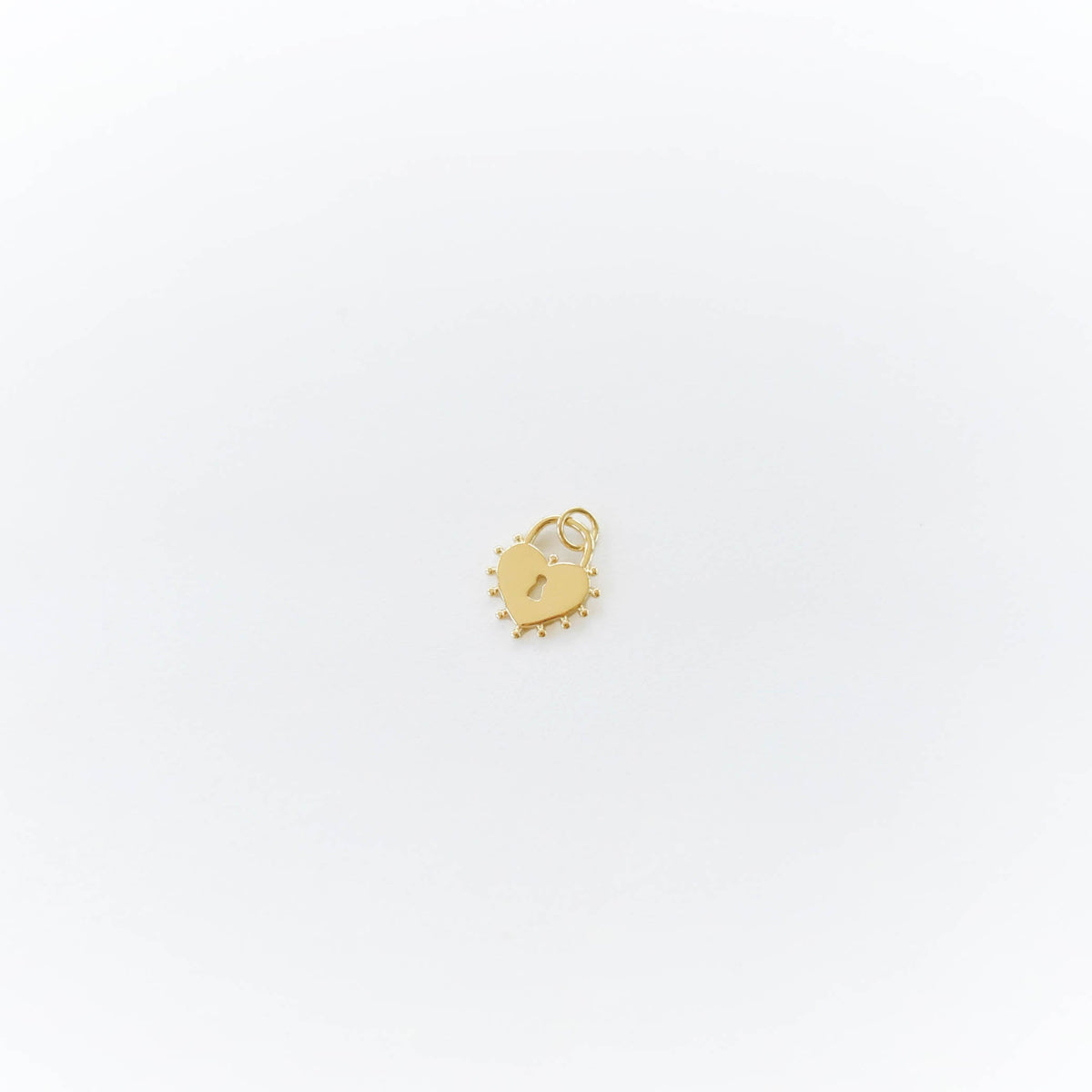 A small gold heart-shaped charm with a spiked border from LLUME Jewelry, perfect for adding to your Build a Charm Necklace, shown on a plain white background.