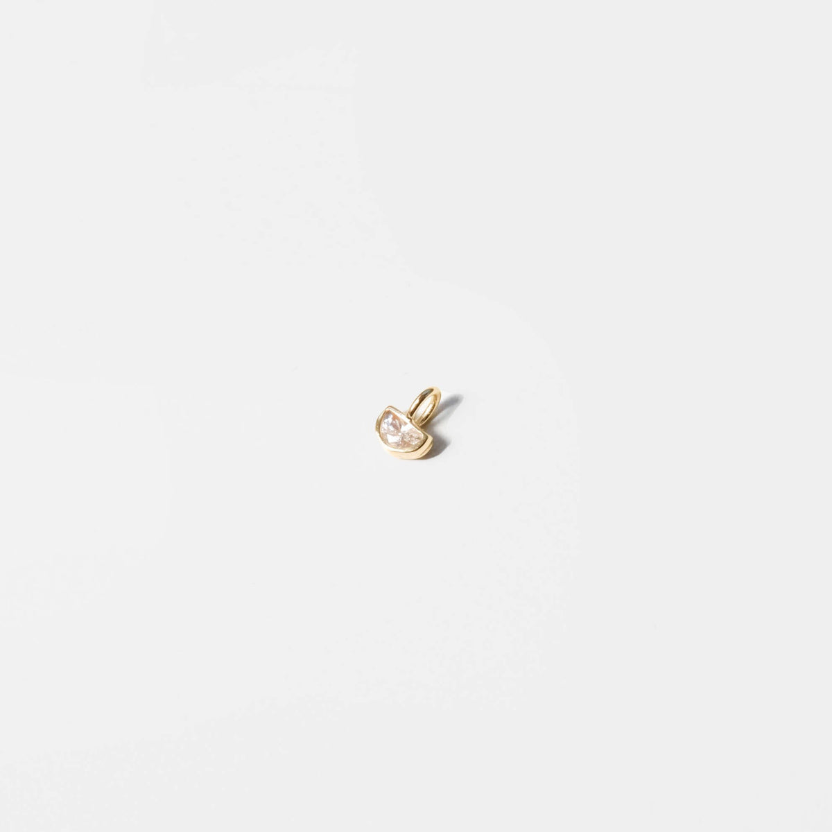 The Build a Birthstone Necklace by LLUME Jewelry features a small gold pendant with a clear gemstone on a plain white background, ideal as a delicate custom charm or birthstone necklace.