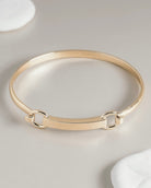 Gold bangle bracelet with bar and hardware clasp detail
