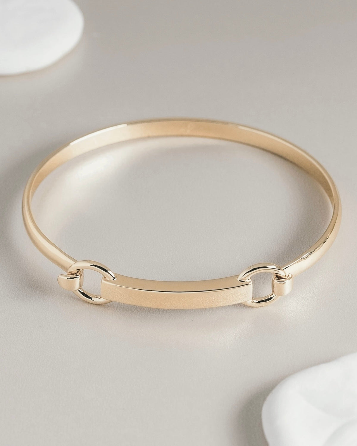 Gold bangle bracelet with bar and hardware clasp detail
