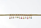 LLUME Jewelry's Birthstone Earrings feature ten gold-plated hoops, each with a unique gemstone charm, displayed on a gold rod—ideal for personalized gifts or birthstone jewelry.