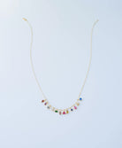 The LLUME Jewelry Build a Birthstone Necklace features gold-plated custom charms and small, colorful birthstone gems in various shapes, evenly spaced along the lower chain, displayed on a plain light background.