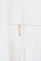 The LLUME Jewelry Build a Charm Necklace features a delicate gold chain with a heart-topped key pendant, perfect for personalization. Shown on a plain white background.