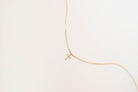 The LLUME Jewelry Cross Necklace showcases a dainty gold-plated chain with a cross pendant, elegantly displayed against a simple light background.