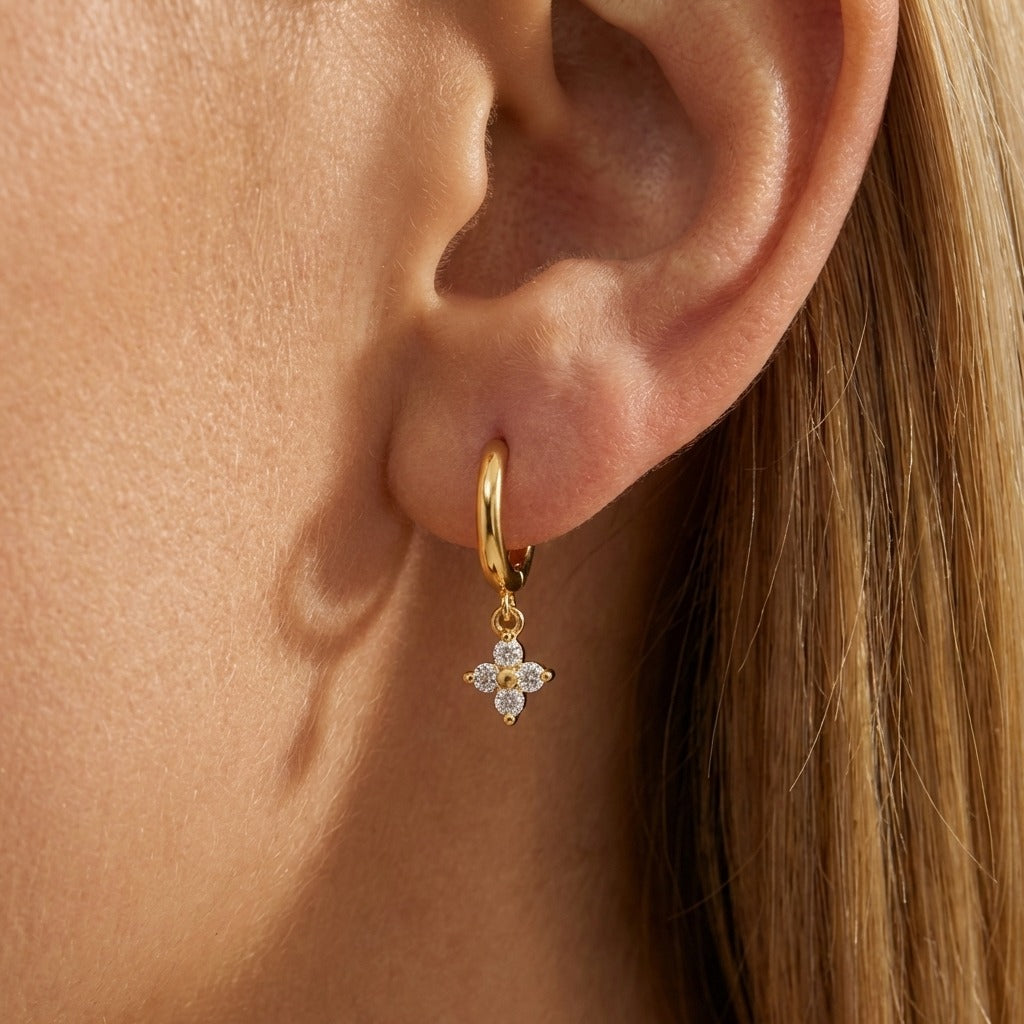 Woman wearing the Mia crystal clover earring, a clear crystal clover charm below a gold huggie