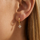 Woman wearing the Mia crystal clover earring, a clear crystal clover charm below a gold huggie
