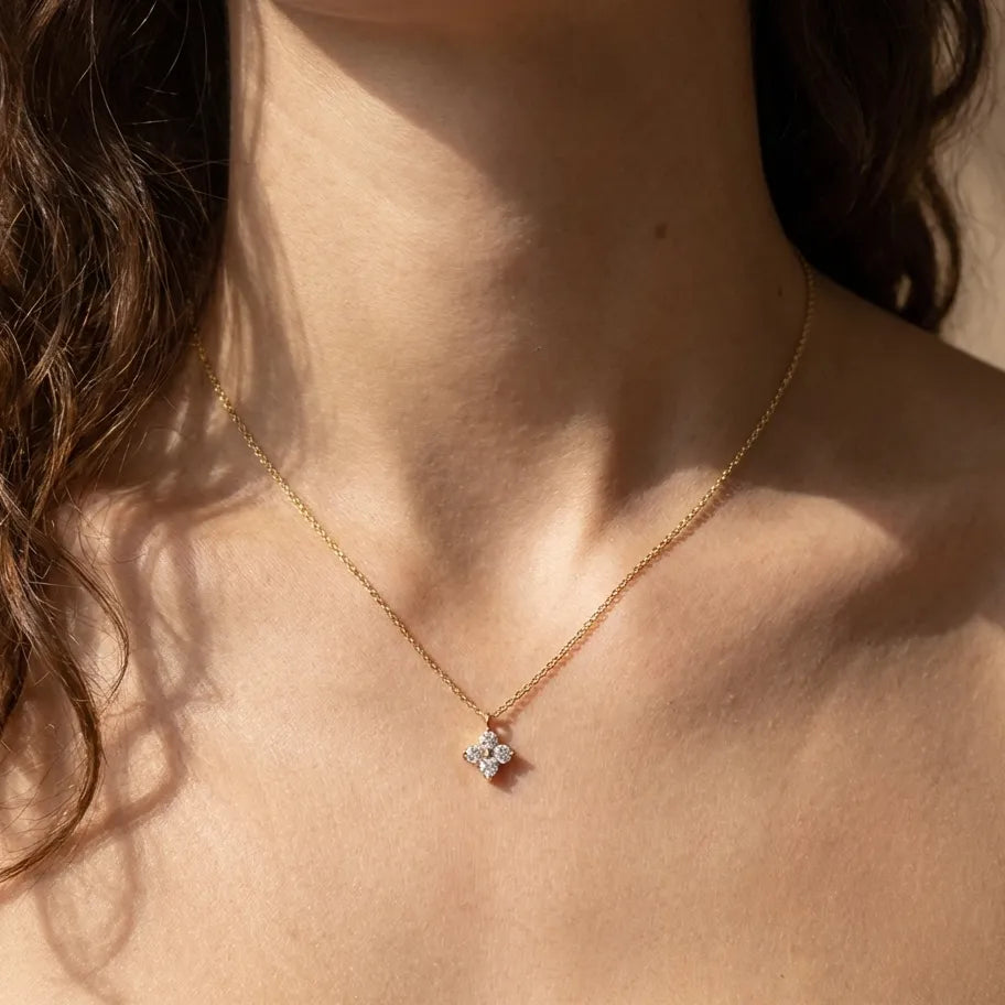 Woman wearing the Mia gold necklace with a four-crystal cluster pendant at the collarbone