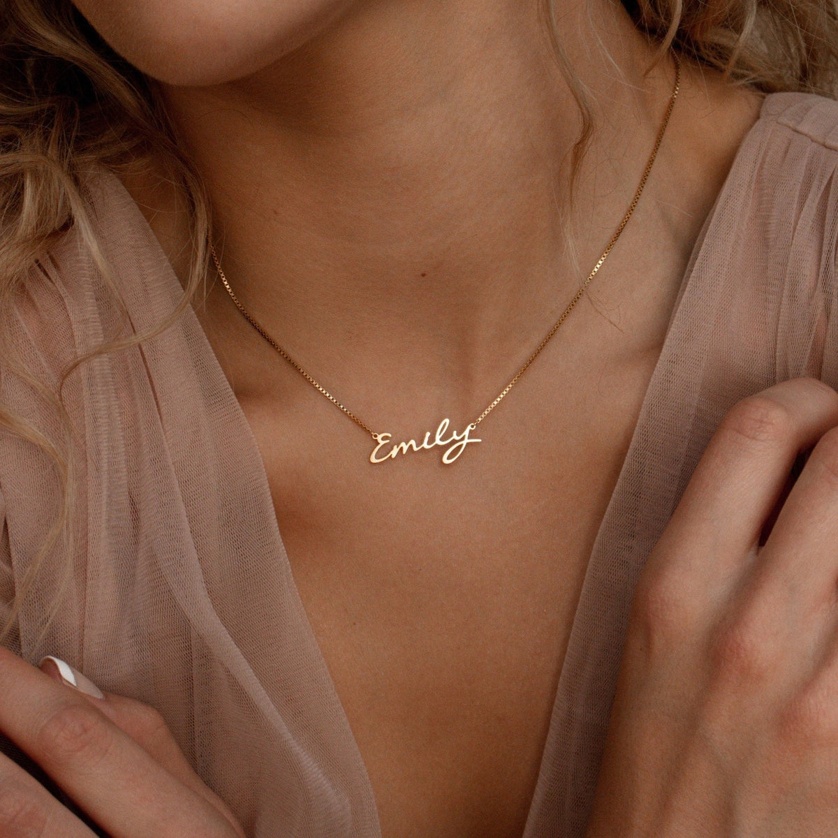 A woman wears the Callie Box Chain Name Necklace in 18K Gold, featuring "Emily" in cursive on a delicate chain.