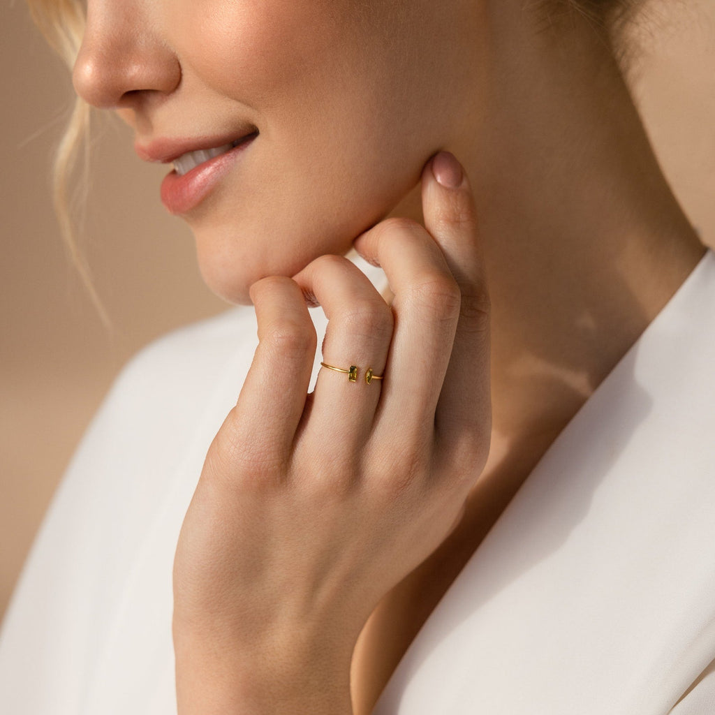 A woman smiles softly in a white top, gently touching her face while wearing the handmade Duo Marquise Baguette Ring.