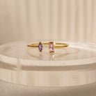 The Duo Marquise Baguette Ring showcases a purple marquise and a pink baguette stone on a translucent band. Experience the allure of handcrafted jewelry with this personalized gemstone ring.