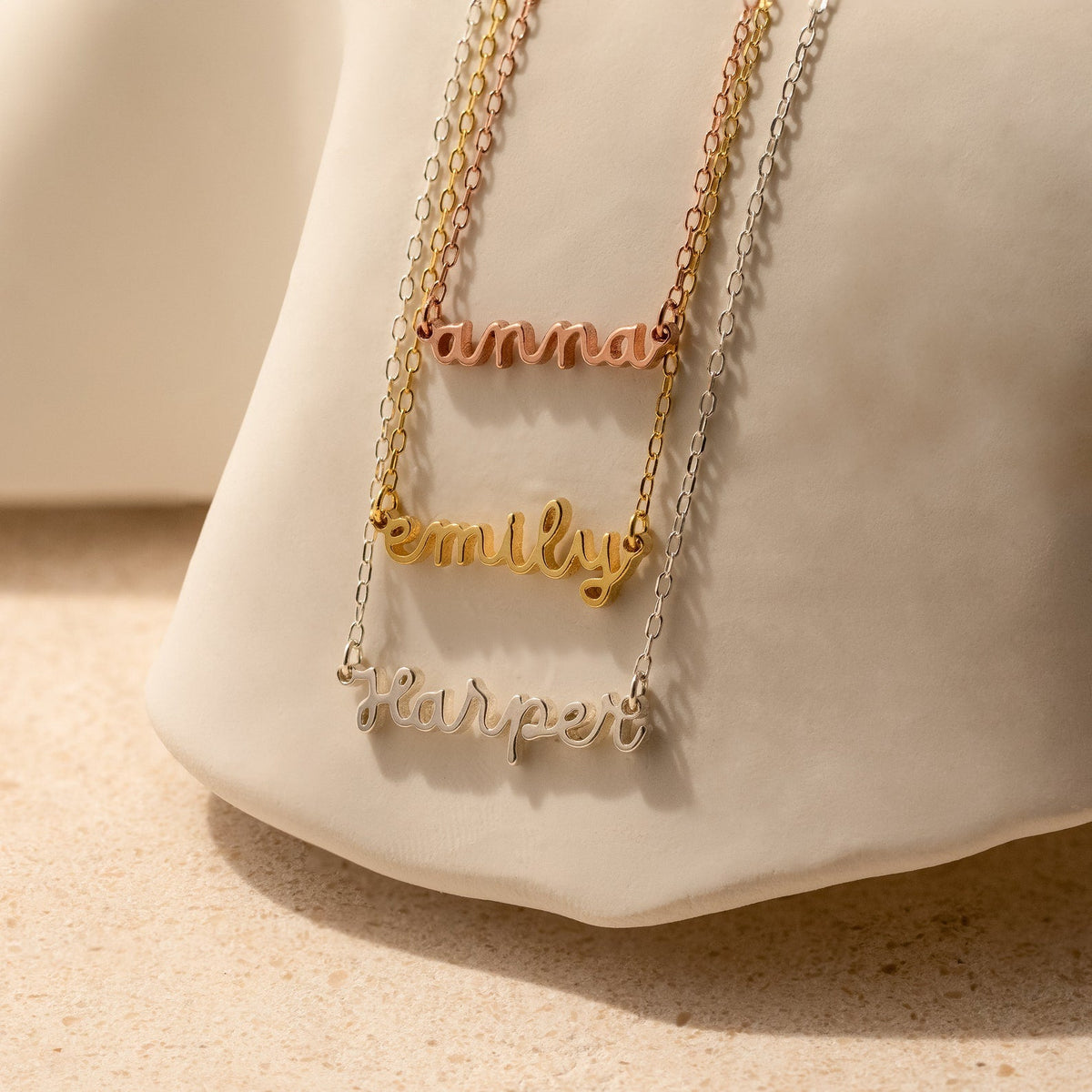Three Tiny Dream Name Necklaces featuring the names hannah, emily, and harper in gold, rose gold, and silver, each crafted in delicate cursive for a personalized touch.