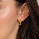 Close-up of a person wearing the Mini Bold Hoops Set in their left ear, highlighting the timeless charm of these classic gold earrings.