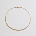 The Marie Chain by LLUME Jewelry is a delicate, thin gold bracelet with a small clasp, shown in a circle on a white background. Perfectly pairs with any 18k gold-filled necklace for an elegant, coordinated style.