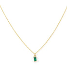 The Kismet Necklace features a simple and elegant gold-plated chain with a small, rectangular emerald green charm pendant set in gold, beautifully centered on the delicate chain.