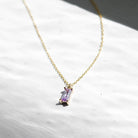The Celia Necklace by LLUME Jewelry is a delicate gold vermeil piece featuring a small rectangular lilac gemstone pendant, displayed on a white textured surface in natural light.
