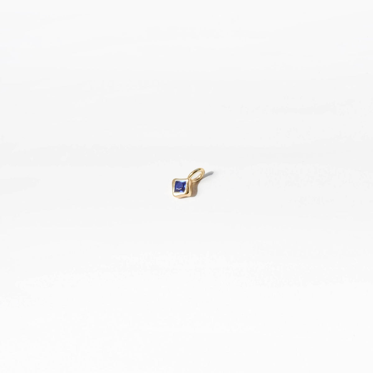 The Build a Birthstone Necklace by LLUME Jewelry features a small gold-plated charm pendant with a square blue gemstone at its center, ideal for customizing your own birthstone necklace. Shown on a plain white background.