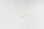 The LLUME Jewelry Build a Birthstone Necklace features a delicate gold chain with elongated links and gold plated charms, beautifully displayed against a plain white background.