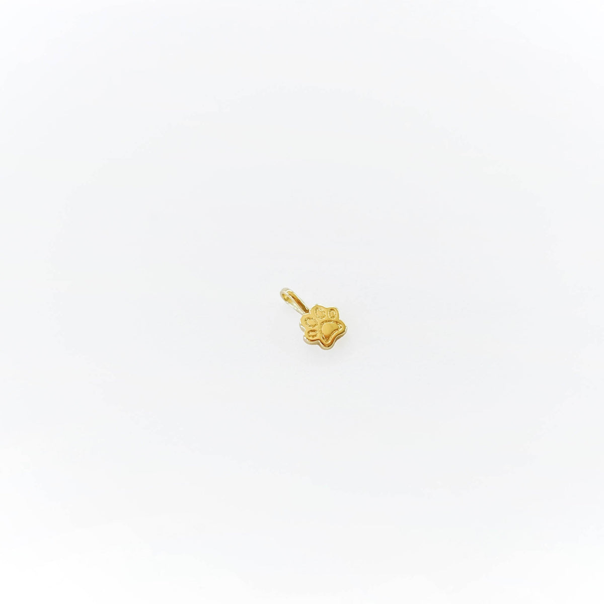 A small gold paw print pendant by LLUME Jewelry, ideal for personalizing your Build a Charm Necklace, shown on a plain white background.