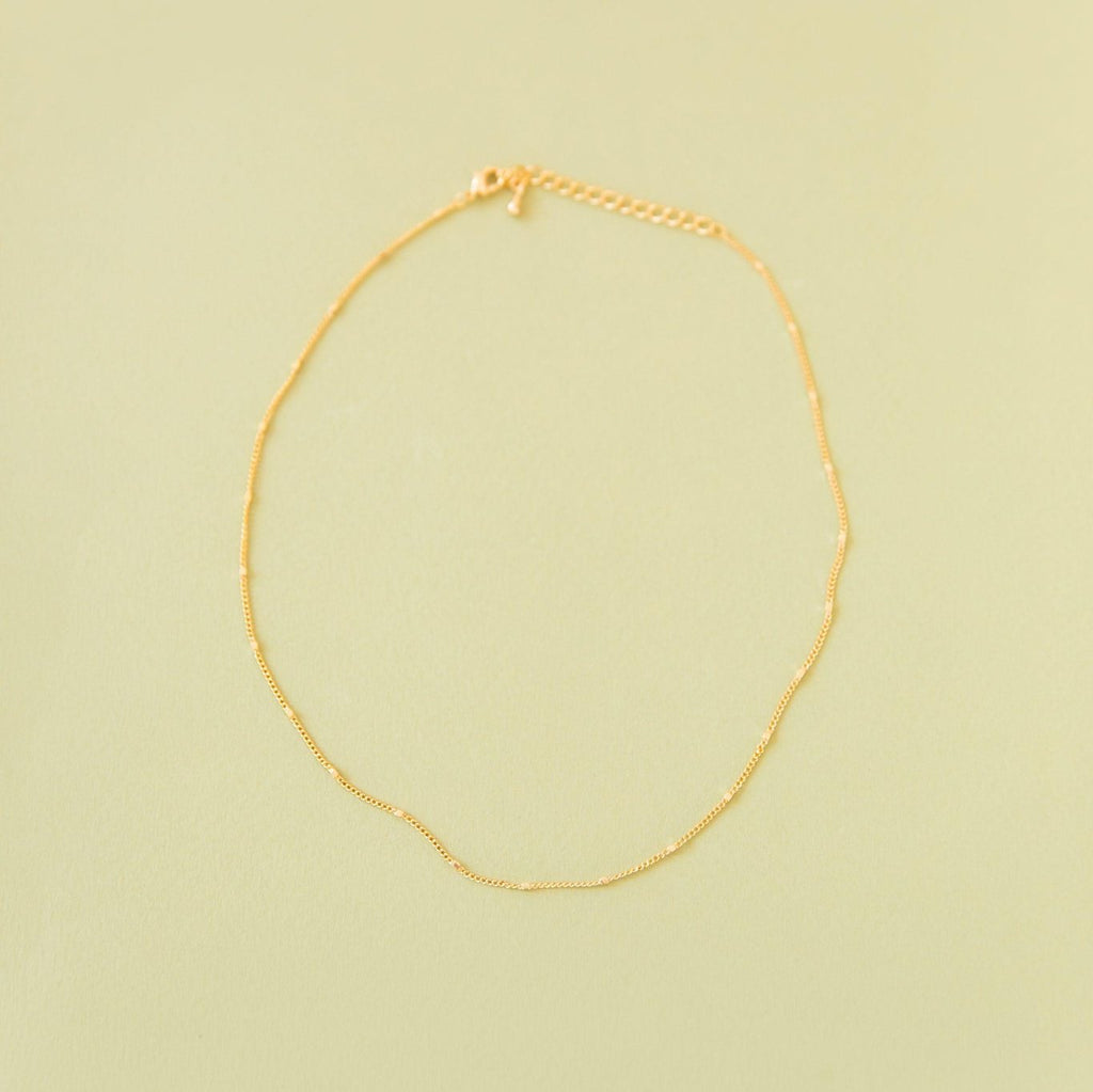 The Linden Chain by LLUME Jewelry, crafted in 18K gold-plated metal with an adjustable clasp and extension, is displayed flat on a pale yellow background.