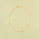 The Linden Chain by LLUME Jewelry, crafted in 18K gold-plated metal with an adjustable clasp and extension, is displayed flat on a pale yellow background.
