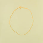 The Linden Chain by LLUME Jewelry, crafted in 18K gold-plated metal with an adjustable clasp and extension, is displayed flat on a pale yellow background.