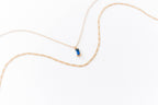 The LLUME Jewelry Taylor Daily Set features a delicate gold pendant necklace with a thin chain and small rectangular blue gemstone, paired with a second slim gold chain—ideal for an elegant layered look.